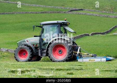 Weide auf einer Hochlandweide, mit einem Hurlimann-Traktor und Fleming-Topper, die von Binsen freigeräumt wird. North Yorkshire, Großbritannien. Stockfoto