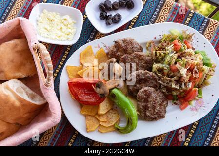 Alanya, Türkei. April 2021. Typische türkische Kofte-Mahlzeit mit grünem Pfeffer, Pilzen, Salat und Pommes frites. (Foto von John Wreford/SOPA Images/Sipa USA) Quelle: SIPA USA/Alamy Live News Stockfoto