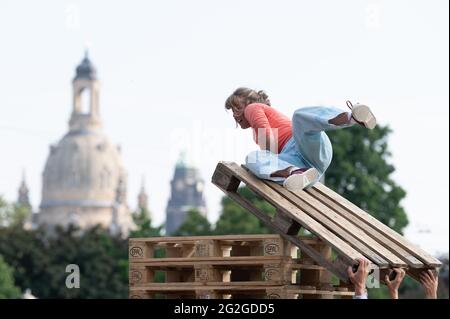 Dresden, Deutschland. Juni 2021. Ein Künstler der kleinen Zirkusgruppe 'FahrAway' aus der Schweiz liegt bei einer Performance vor der Kulisse der Frauenkirche auf einem Stapel Euro-Paletten. Die Performance ist Teil des Programms des Societatheaters Dresden. Quelle: Sebastian Kahnert/dpa-Zentralbild/dpa/Alamy Live News Stockfoto