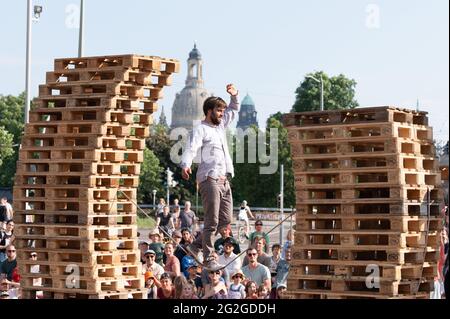 Dresden, Deutschland. Juni 2021. Ein Künstler der kleinen Zirkusgruppe 'FahrAway' aus der Schweiz balanciert auf einem Seil zwischen zwei Euro-Paletten-Stapeln während einer Performance vor der Kulisse der Frauenkirche. Die Performance ist Teil des Programms des Societatheaters Dresden. Quelle: Sebastian Kahnert/dpa-Zentralbild/dpa/Alamy Live News Stockfoto