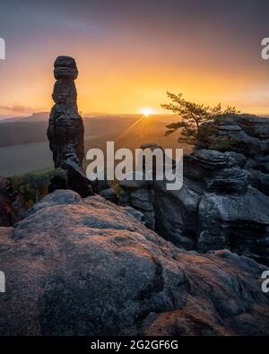 Farbenprächtiger Sonnenaufgang hinter der Barbarine auf dem Pfaffenstein im Elbsandsteingebirge. Stockfoto