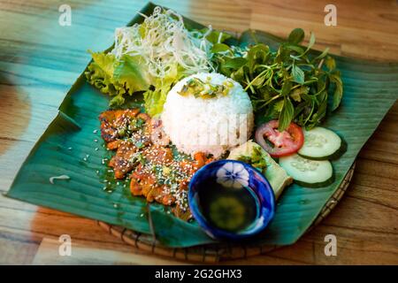 Gebrochener Reis mit Schweinekotelett und Gemüse - Com Tam Suon.traditionelle vietnamesische Küche im Restaurant im Zentrum von Hue, Vietnam serviert. Stockfoto
