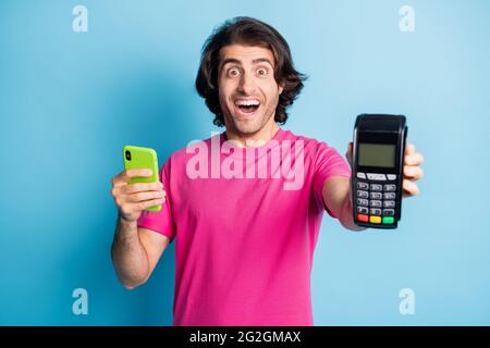 Porträt von schönen erstaunt fröhlich Kerl hält in den Händen Gadget POS Terminal Cyber Kauf App isoliert über hellen blauen Hintergrund Stockfoto