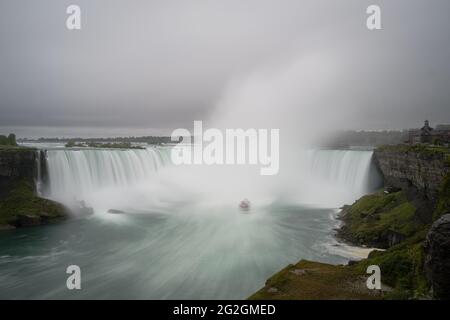 Panoramablick auf die Niagarafälle-Tour Boot, das in den Horseshoe Falls Wasserfall segelt, mit Wassernebel, der nach oben in Richtung Himmel driftet, Ontario, Kanada Stockfoto