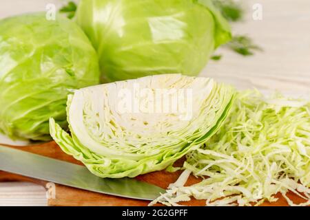 Frischer Weißkohl und gehackter Kohl für den Salat auf einem hölzernen Schneidebrett. Vegetarische und gesunde Ernährung Lebensmittelkonzept. Stockfoto