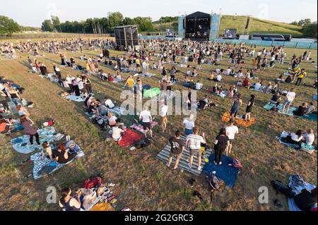 Dresden, Deutschland. Juni 2021. Das Publikum steht und sitzt auf der Wiese während eines Konzerts der Band Meute, das Teil der Reihe „Picknick-Konzerte“ auf dem Messegelände ist. Das Konzert ist auch das erste Open-Air-Event nach der Sperre in der Landeshauptstadt. Quelle: Sebastian Kahnert/dpa-Zentralbild/dpa/Alamy Live News Stockfoto