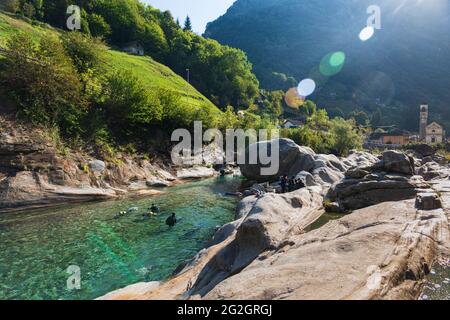 Schweiz, Tessin, Verzasca Valley, Verzasca, Taucher im Fluss am beliebten Becken mit den Granitfelsen. Streulicht. Stockfoto