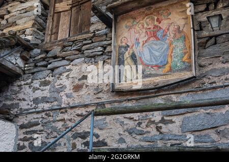 Impressionen von Lavertezzo im Verzasca-Tal, Bezirk Locarno, Kanton Tessin in der Schweiz: Beliebtes Ausflugsziel zum Wandern, Flusstauchen und Schwimmen. Historisches Stadtzentrum, Ikone an einer Hausmauer. Stockfoto