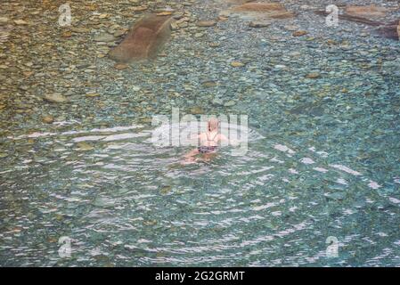 Impressionen von Lavertezzo im Verzasca-Tal, Bezirk Locarno, Kanton Tessin in der Schweiz: Beliebtes Ausflugsziel zum Wandern, Flusstauchen und Schwimmen. Frau badet im kristallklaren Wasser der Verzasca Stockfoto