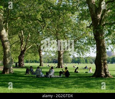 London, Greater London, England - 27. Mai 2021: Freunde sitzen und plaudern an einem sonnigen Frühlingstag im Hyde Park. Stockfoto