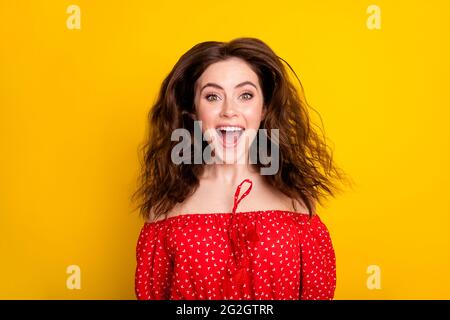 Foto-Porträt von glücklichen Mädchen mit welligen Haaren in rotem Hemd erstaunt Springen bis Lachen isoliert lebendige gelbe Farbe Hintergrund Stockfoto