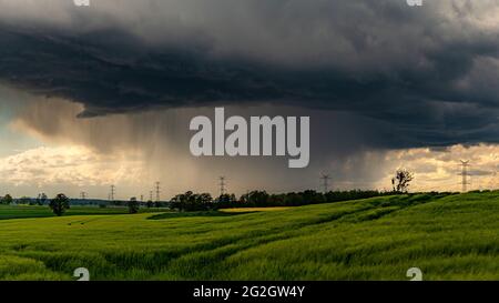 Dunkler stürmischer Himmel über einer grünen Wiese Stockfoto
