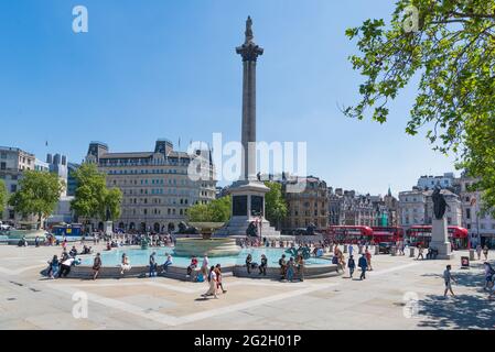 Menschen unterwegs, entspannen und genießen einen warmen, sonnigen Tag auf dem Trafalgar Square, London, England, Großbritannien Stockfoto