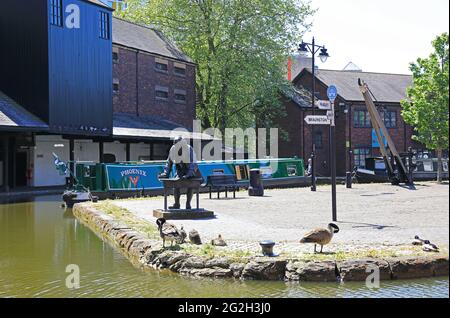 Statue von James Brindley, der den Coventry-Kanal im Bishop Street Basin errichten ließ, umgeben von historischen Lagerhäusern und Lastkähnen, Großbritannien Stockfoto