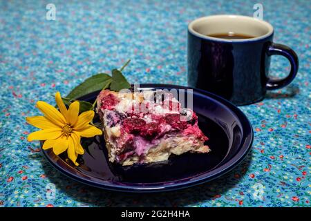 Heidelbeer, Himbeer-Croissant-Puff-Dessert mit Kaffee und einer Sonnenblume auf einer blühenden blauen Tischdecke. Stockfoto
