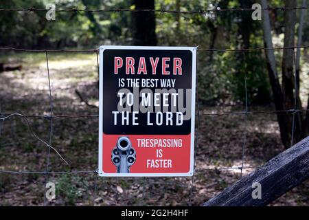 Brooksville, Florida, USA. Juni 2021. Ein Schild an einem Zaun warnt potenzielle Eindringling, sich von privatem Land zu halten oder sich einer Waffe zu stellen, was darauf hindeutet, dass das Anwesen von Besitzern geschützt wird, die religiös sind, an den Zweiten Änderungsantrag glauben und bereit sind, Straftäter zu erschießen. Quelle: Robin Rayne/ZUMA Wire/Alamy Live News Stockfoto