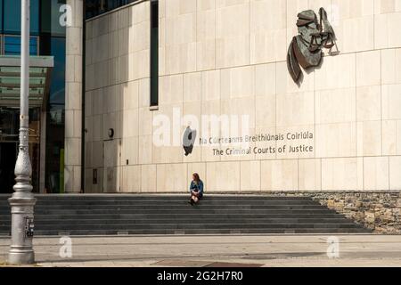 Gerichtshof Irland der Strafgerichtshof und eine junge Frau, die auf der Treppe des Strafgerichtshofs Dublin, Irland, sitzt, Stand Juni 2021 Stockfoto