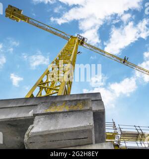 Kran und Gebäude im Bau. Ausgedehnte Gerüste, die Plattformen für die laufenden Arbeiten an einem neuen Wohnblock bieten. Baustelle. Hou Stockfoto