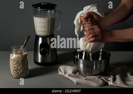 Hafermilch, Strain, Schüssel, Mixer, Einmachglas, Löffel, Küchentuch Stockfoto