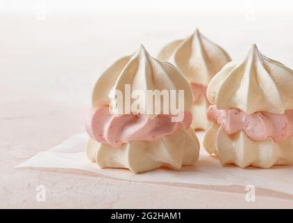 Kleine Baiser-Kuchen aus Eiweiß-Keksen und Erdbeercreme auf rosa Hintergrund Stockfoto