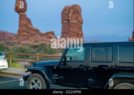 Wrangler Jeep auf dem Parkplatz am Balanced Rock - ein massiver Felsen, der auf einer schmalen Säule im Arches National Park, in der Nähe von Moab in Utah, USA, ruht Stockfoto