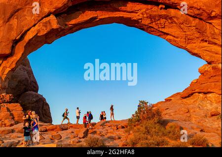 Viele Touristen stehen im North Window Arch. Bogen auf der Nordseite der Fenster, eine Sandsteinflosse mit 2 massiven, augenförmigen Öffnungen im Arches National Park, in der Nähe von Moab in Utah, USA. Stockfoto