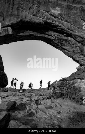 Viele Touristen stehen im North Window Arch. Bogen auf der Nordseite der Fenster, eine Sandsteinflosse mit 2 massiven, augenförmigen Öffnungen im Arches National Park, in der Nähe von Moab in Utah, USA. Stockfoto