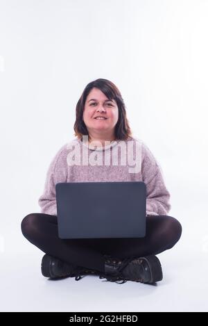 Porträt einer Frau, die mit ihrem PC sitzt und die Kamera auf weißem Hintergrund anschaut. Internet-Shopping-Konzept. Speicherplatz kopieren Stockfoto