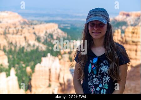 Ein Mädchen, 15-20 Jahre, kaukasisch, dunkelblond, das vor vielen Hoodoos am Sunset Point im Bryce Canyon National Park, Utah, USA, steht Stockfoto