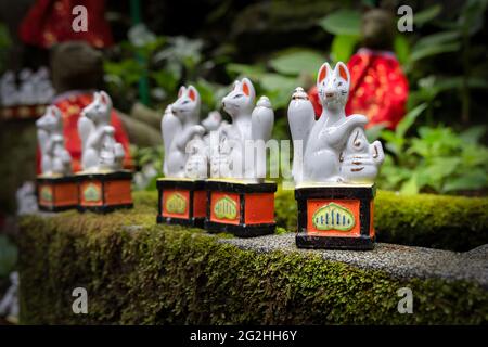 Kleine Fuchsstatuen am Fuß dieses Torii-Toreingangs zu diesem Schrein in Kamakura, Japan. Stockfoto