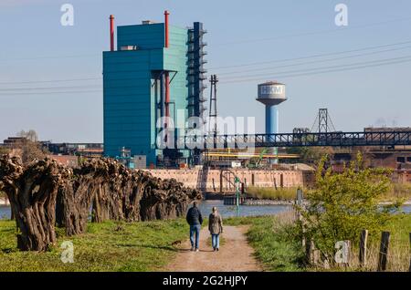 Duisburg, Nordrhein-Westfalen, Deutschland - Industrielandschaft im Ruhrgebiet laufen Kinderwagen vor der industriellen Kulisse der HKM Huettenwerke Krupp Mannesmann auf dem Rhein. Stockfoto