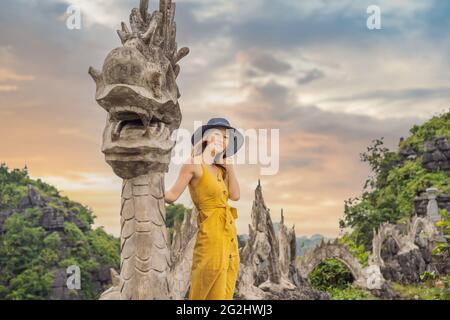 Frau Tourist auf dem Hintergrund der erstaunlichen riesigen Drachenstatue auf Kalkstein Berggipfel in der Nähe Hang Mua Aussichtspunkt am nebligen Morgen. Beliebter Tourist Stockfoto