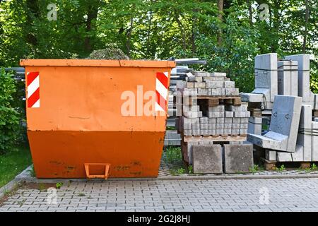 Orange, industriell transportierbare Müllcontainer und Kopfsteinpflaster auf Palette auf der Baustelle Stockfoto