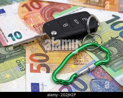 Autoschlüssel mit Karabiner in Autoform auf Euro-Geld-Hintergrund, Konzept der Kfz-Versicherung Stockfoto