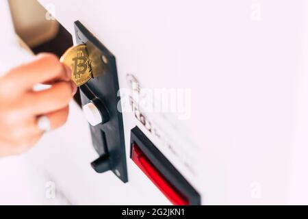 Frau steckt eine Bitcoin in den Automaten, Nahaufnahme Stockfoto