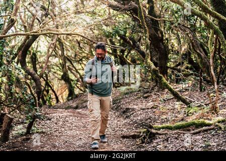 Erwachsene Männer laufen im Wald und nutzen moderne Internet 5g-Technologie mit Telefon - Hipster reife Männer erkunden und genießen Abenteuer allein mit Rucksack und Wald herum Stockfoto