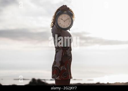 Zeit hinter Zukunft Konzept stehende Frau halten und zeigen große alte Uhr versteckt sein Gesicht - kopieren Raum und klaren Himmel im Hintergrund Stockfoto