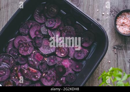 Scheiben lila Karotte mit rosa Salz und Olivenöl zum Rösten. Stockfoto