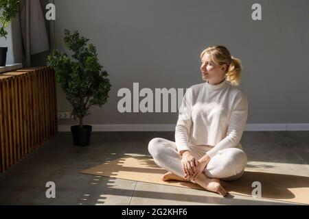 Attraktive blonde Frau in weißer Sportbekleidung, die sich nach dem Sport-Training im Fitnessstudio ausruhte. Stockfoto
