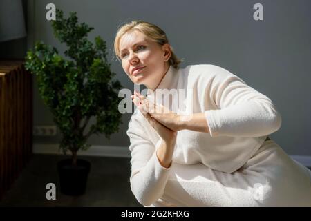 Attraktive Frau mittleren Alters, die im Fitnessstudio Meditation und Yoga macht. Stockfoto