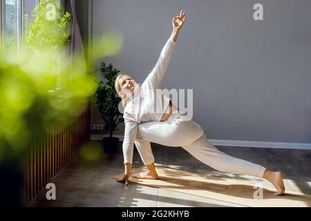 Gesunde, konzentrierte Frau macht Dehnübungen Yoga. Morgendliches Training im Fitnessstudio. Stockfoto