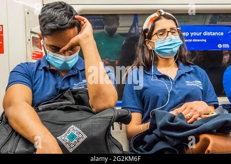 London, Großbritannien. Juni 2021. Erschöpfte Mitglieder des Impfteams von Guy's und St. Thomas fahren in der Londoner U-Bahn nach Hause. Kredit: Guy Bell/Alamy Live Nachrichten Stockfoto