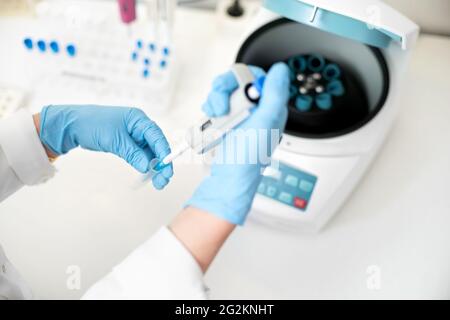 Forscher, der Pipetten- und Analyselabproben in einer Zentrifuge im Labor verwendet. Forscherin platziert Reagenzgläser in der Spezialmaschine. Stockfoto