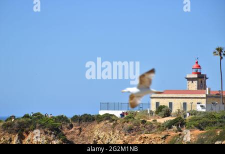 Möwe fliegt vor dem Leuchtturm an der Küste von Lagos, Portugal, Algarve Stockfoto