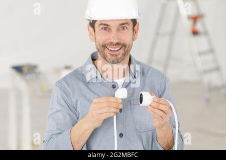 Ein glücklicher Elektriker hält die Kabel in den Händen Stockfoto