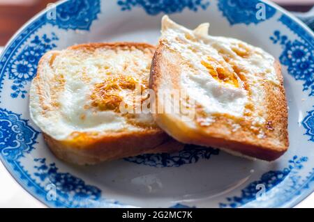 Eierbrot auf dem Teller, fotografiert mit natürlichem Licht. Golden French Toast mit Butter und Ei. Frühstück mit Brot. Englisches Frühstück. Gesundes Frühstück Stockfoto