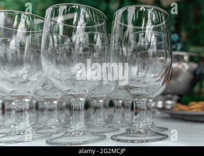 Leere Glas transparente Weingläser auf einem Tisch auf einem verschwommenen Hintergrund. Weingläser in Reihe. Selektiver Fokus, Nahaufnahme. Stockfoto
