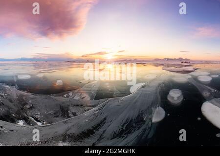 Landschaft rosa Wolken bei Sonnenaufgang auf Kap khoboy olchon Insel Baikalsee im Winter auf Eis mit rissigen und großen weißen Blasen. Stockfoto