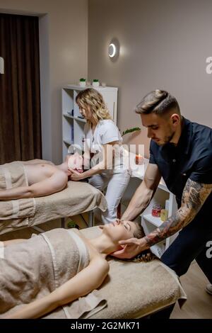 Schöne junge Frau, die sich mit ihrem Partner während der traditionellen Thai-Massage im Luxus-Spa und Wellness-Center entspannt. Stockfoto