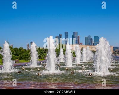 Jets von Springbrunnen an einem sonnigen Tag vor der Kulisse moderner Wolkenkratzer und einem wolkenlosen blauen Himmel. Erholungsgebiet im Victory Park auf Poklonnaya Stockfoto